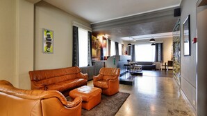 A spacious living area with a leather sofa, ottoman, and a dining area with a table and chairs. - Holiday home in Marcourt with garden (Rendeux)