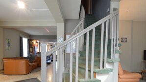 A spacious living area with a curved staircase, a sofa, and a television. - Holiday home in Marcourt with garden (Rendeux)