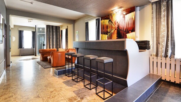 A modern lobby with a seating area, a bar, and a fireplace. - Holiday home in Marcourt with garden (Rendeux)