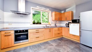 A modern kitchen with wooden cabinets, a built-in oven, a microwave, and a dishwasher.