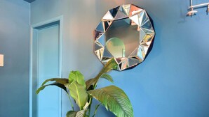 A hallway with a blue wall, a round mirror, and a potted plant.