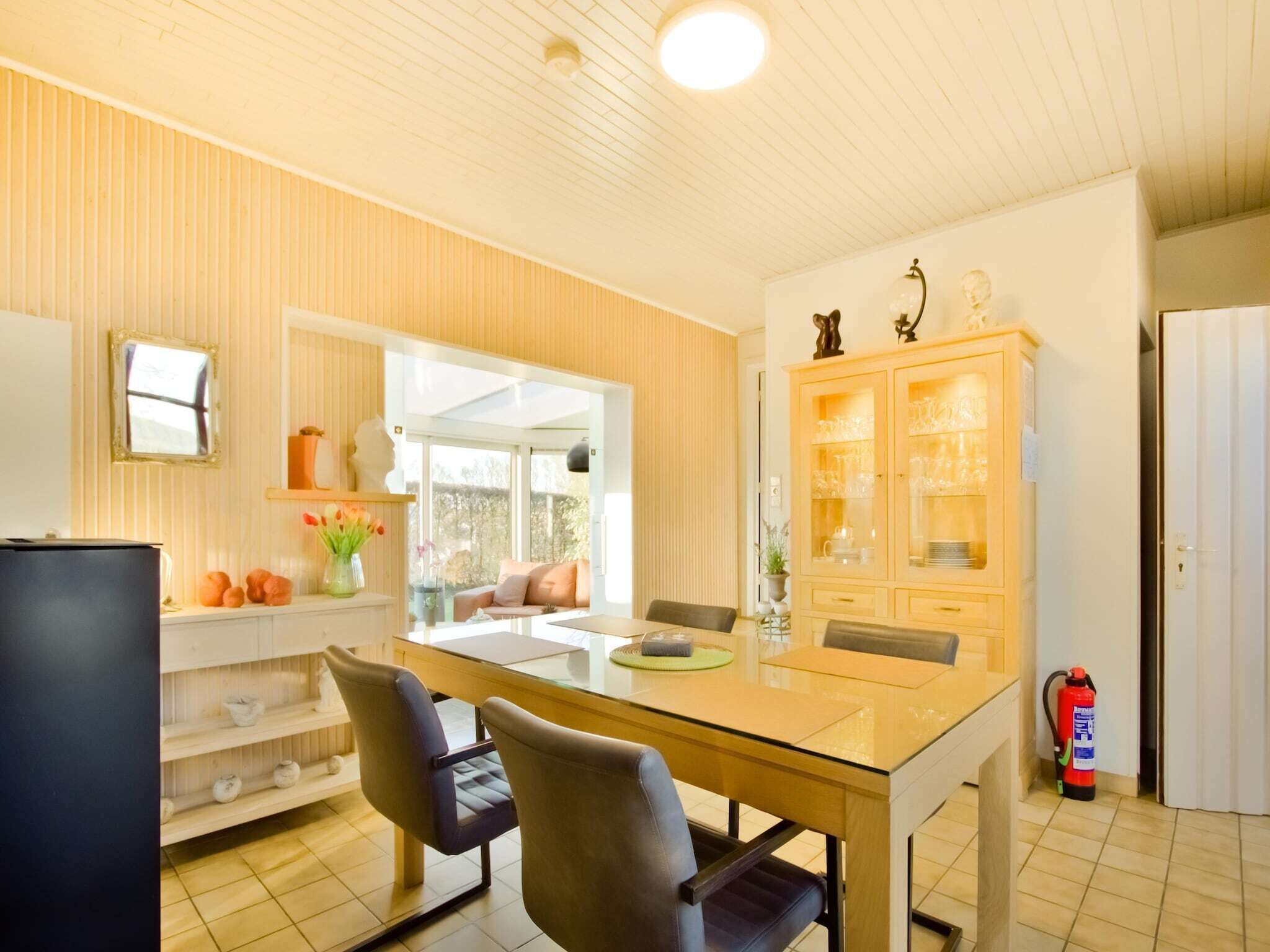 Eine moderne Küche mit Esstisch, Stühlen, einem Schrank mit Glastüren und einem Fenster.