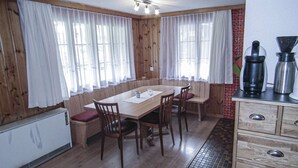 A wooden-paneled room with a dining table, chairs, a radiator, and a kitchenette with a coffee maker. - Chalet in Lenk near Simmen Falls (Lenk)