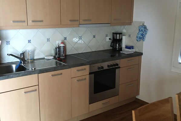 A kitchen with wooden cabinets, a stainless steel sink, and a built-in oven. - Spacious Apartment in Riederalp near Ski Trail (Riederalp)
