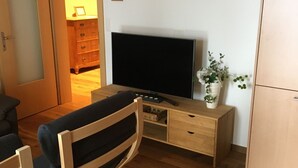 A room with a wooden desk, a television, a chair, a cabinet, and a potted plant.