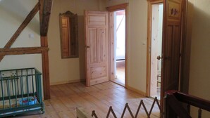 Une pièce avec un plancher en bois, un berceau et une porte donnant sur une autre pièce.