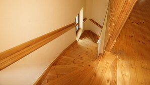 A wooden staircase with a handrail, leading to a landing with a small window.