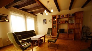 A cozy living room with a wooden floor, a green sofa, a wooden coffee table, and a bookshelf filled with books.