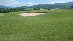 A golf course with a sand bunker, trees, and distant mountains. - Serene Holiday Home in Mladé Buky with small pool, Trampoline & Skiing Nearby (Mladé Buky)