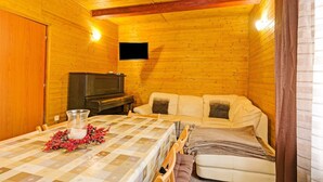 A cozy cabin interior with a wooden interior, a dining table with a checkered tablecloth, a sofa, and a television. - Mountain Home with Garden (Černý Důl)