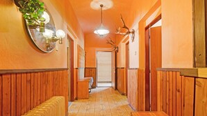 A hallway with wooden walls, a tiled floor, a bench, a mirror, a light fixture, and a door at the end. - Mountain Home with Garden (Černý Důl)