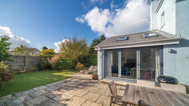 A patio with a wooden table and chairs, a barbecue grill, and a glass door leading to a covered outdoor area. - San Rocco -  a dog friendly cottage that sleeps 6 guests  in 3 bedrooms (Bembridge)