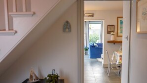A staircase leading to a living area with a blue sofa, a small sailboat model, and a plant on a black cabinet. - San Rocco -  a dog friendly cottage that sleeps 6 guests  in 3 bedrooms (Bembridge)