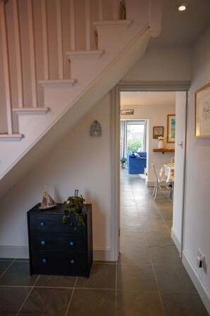 Stairs lead to a cozy living area with a sofa, chair, and decorative shelf.