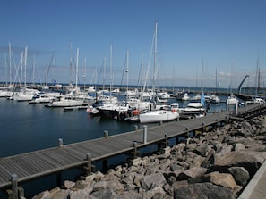 Explore the tranquil marina with sailboats docked at piers, accessible via wooden walkways.