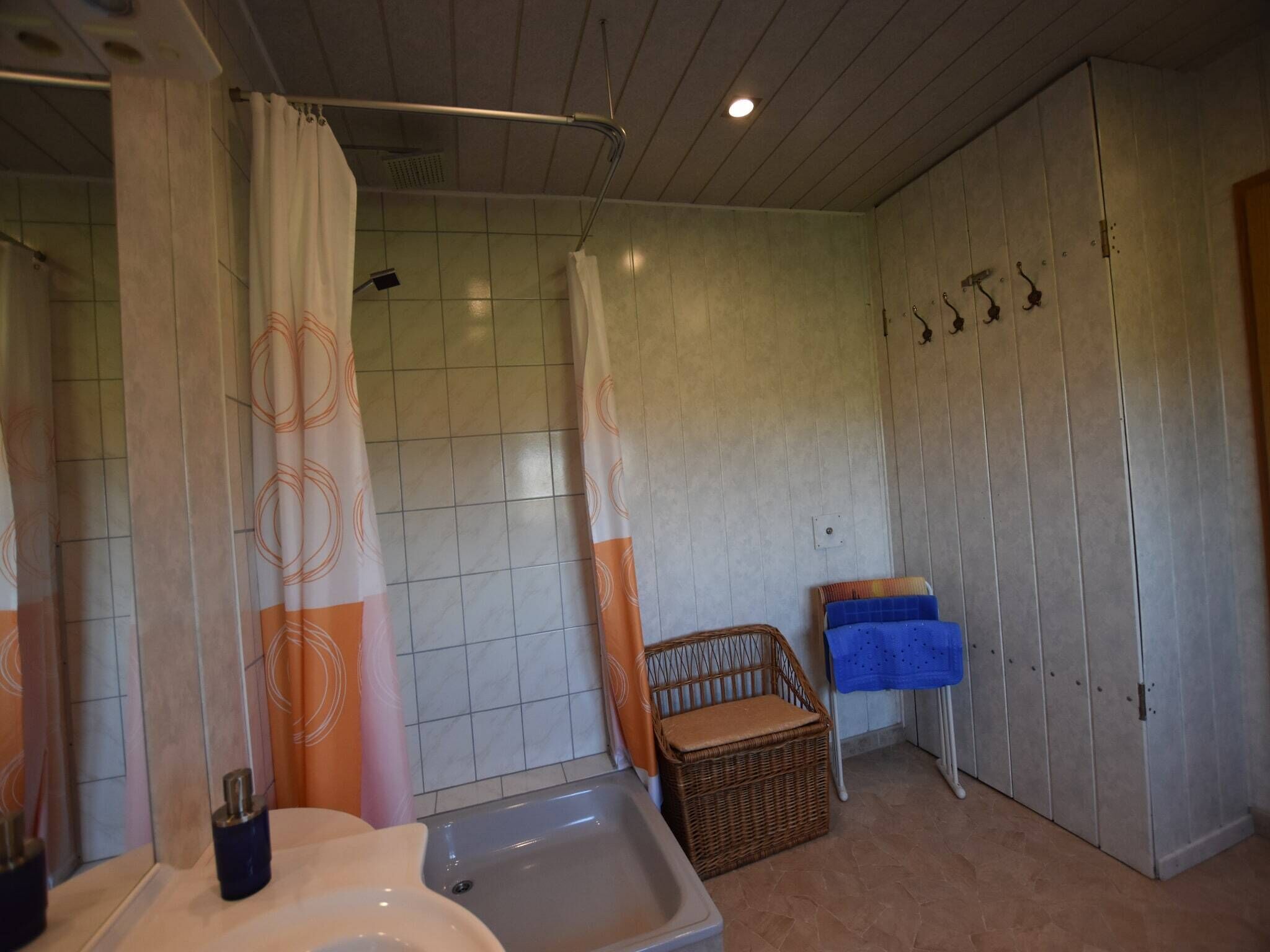 Une salle de bain avec une douche, un lavabo, un panier en osier et un porte-serviettes.