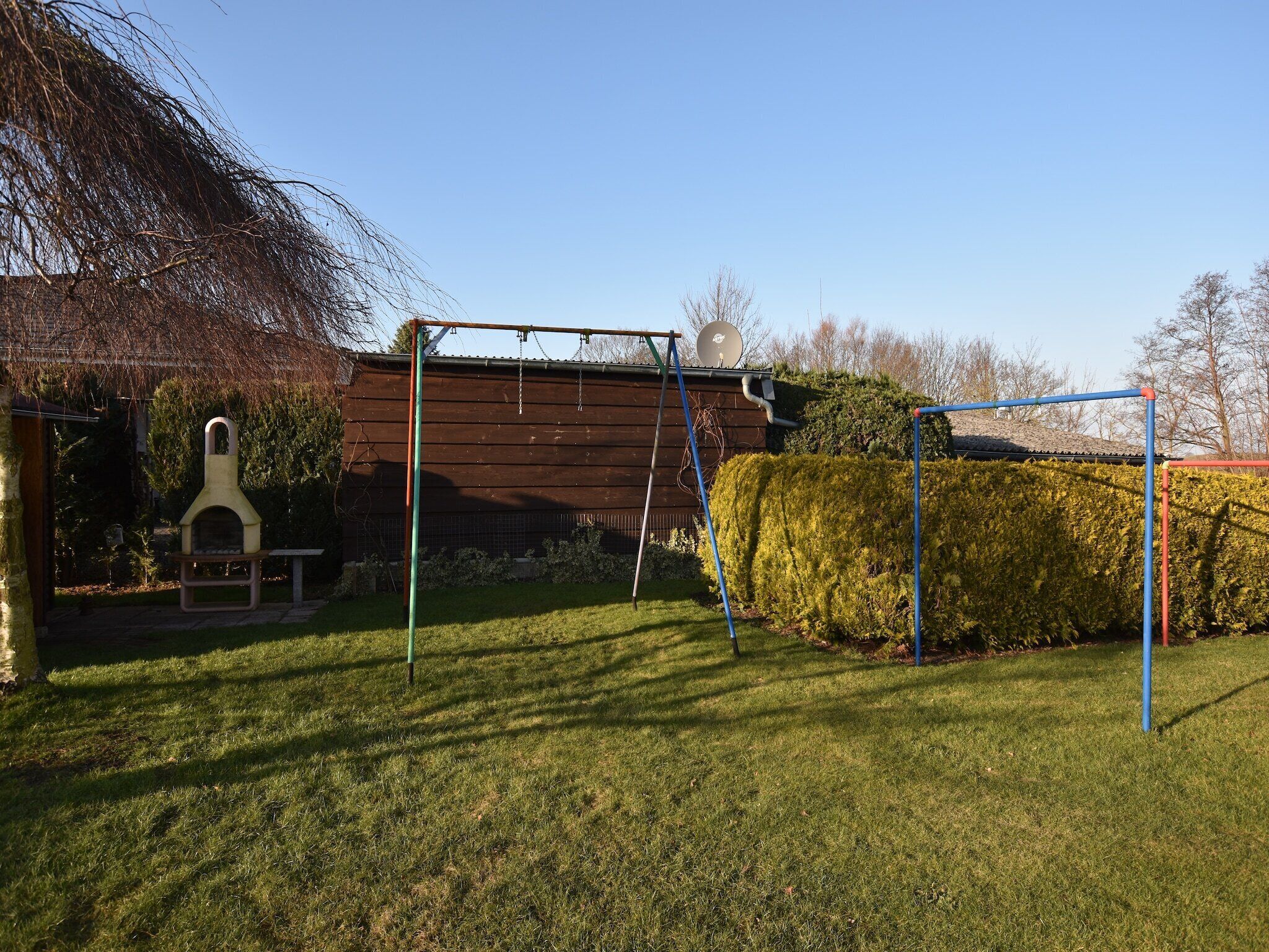 A backyard with a swing set, a wooden shed, and a satellite dish.