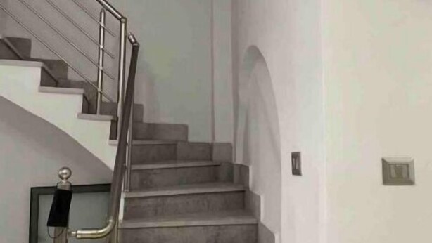 Uma escada com corrimão de metal, que leva a um andar superior.