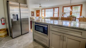 Una cocina moderna con electrodomésticos de acero inoxidable, microondas integrado y una isla grande con cubierta de vidrio.