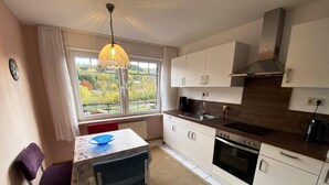 A modern kitchen with white cabinets, a built-in oven, and a window with a view of greenery.