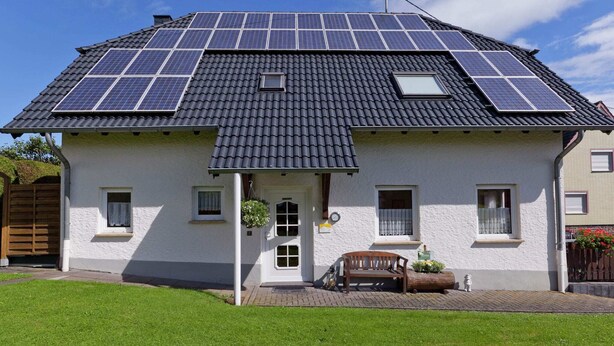 Uma casa com telhado ladrilhado e painéis solares.