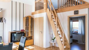 A spacious living area with a wooden staircase, a television, and a dining area with chairs. - Flat in Beltheim (Germany) with pool (Beltheim)