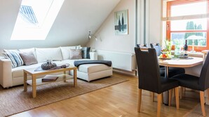 A modern living room with a white sofa, a wooden coffee table, and a dining area with a table and chairs. - Flat in Beltheim (Germany) with pool (Beltheim)
