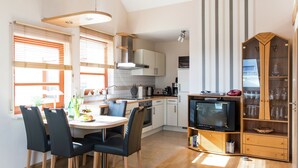 A modern kitchen with a dining area, wooden cabinets, and a built-in TV. - Flat in Beltheim (Germany) with pool (Beltheim)