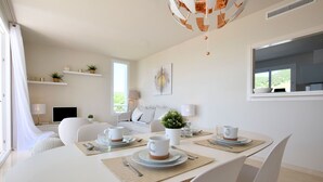 A modern dining area with a round table set for four, white chairs, and a ceiling light fixture. - Belvilla by OYO Alcazaba Lagoon (Casares)