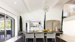 Un comedor moderno con una mesa grande, sillas blancas y un tapete oscuro.