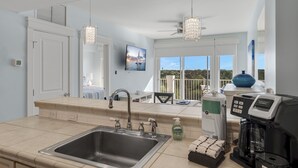 A modern kitchen with a large sink, a coffee maker, and a view of the outdoors.