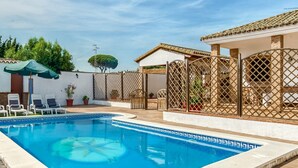 Une piscine avec des chaises longues et une pergola.