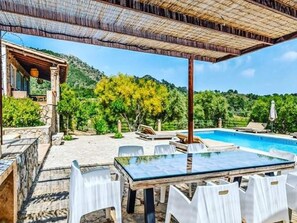Relax by the pool in a serene outdoor setting surrounded by lush greenery and a nearby building.