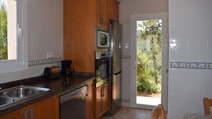 Una cocina con armarios de madera, un refrigerador de acero inoxidable, un horno y un lavavajillas.