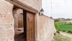A rustic building with a wooden door and a lantern on the wall.