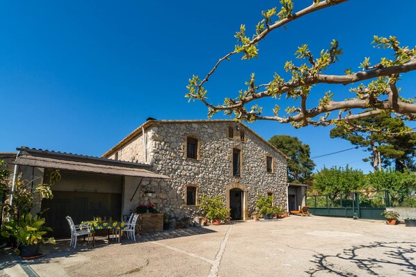 A stone building with a covered patio, outdoor seating, and potted plants.
