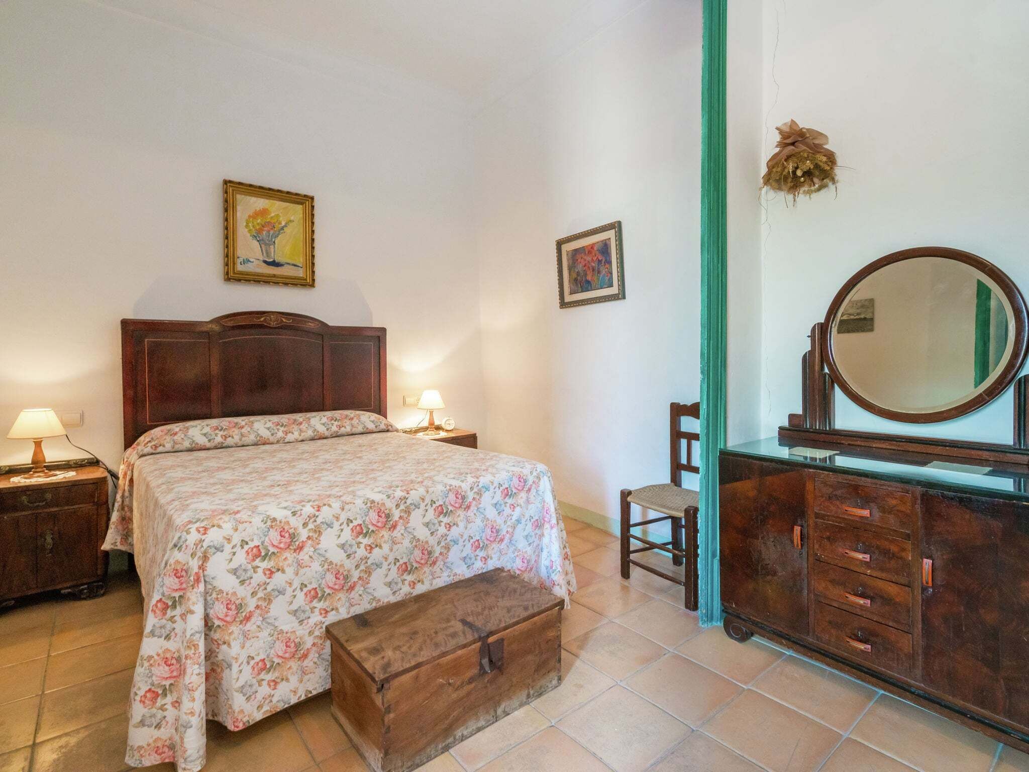 Un dormitorio con cama de madera, cómoda, espejo y dos lámparas fijadas a la pared.