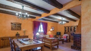 Un comedor rústico con muebles de madera, una araña y una chimenea de ladrillo.