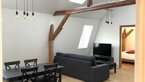 A modern living space with a dining area, a sofa, a TV, and skylights. - Apartment Cypress (Stutzheim-Offenheim)