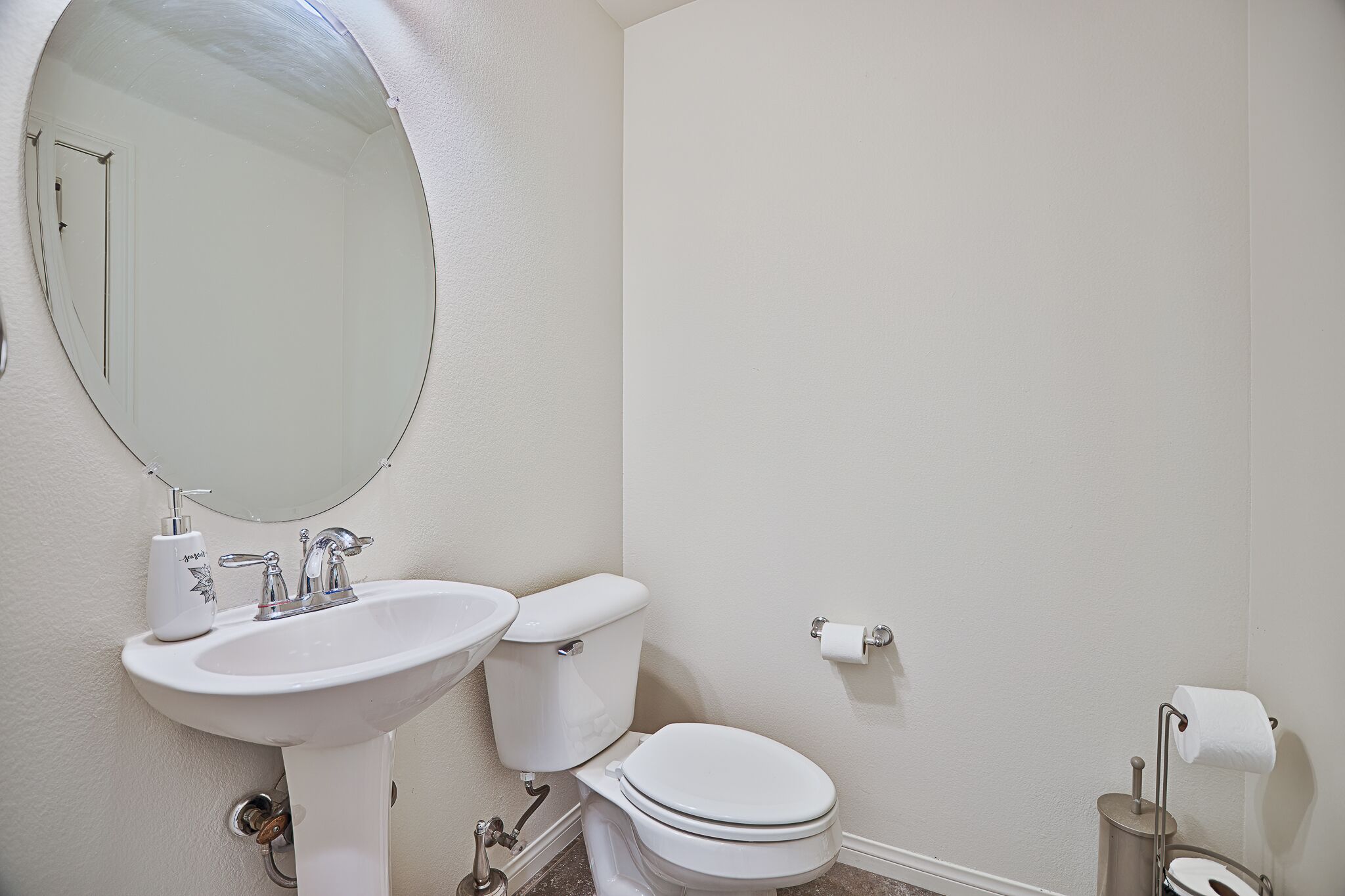 Et badeværelse med et hvidt håndvask, toilet og et stort spejl.