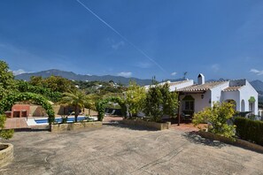 A residential area with a white house, a swimming pool, and mountains in the background. - Lopera Cave Apartment with View (Frigiliana)