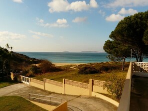 Vista costera con una playa, una cerca y un camino que lleva a la playa.