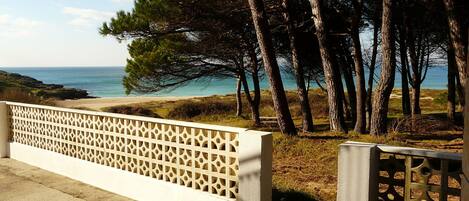 A coastal view with a white lattice fence, trees, and a clear sky.