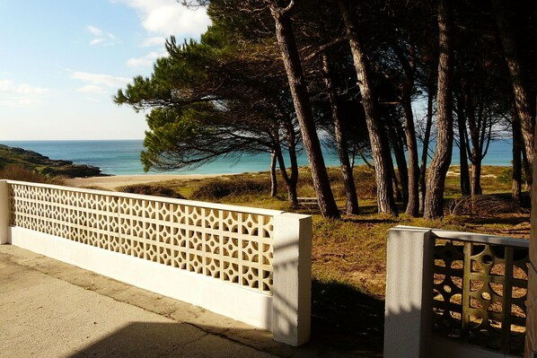 A coastal view with a white lattice fence, trees, and a clear sky.