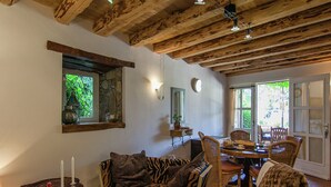 A cozy room with a wooden ceiling, a zebra-patterned sofa, wicker chairs, and a dining table set for two.