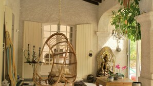 A room with a hanging chair, a Buddha statue, and a plant. - Luxury villa with heated jacuzzi and garden (Le Muy)