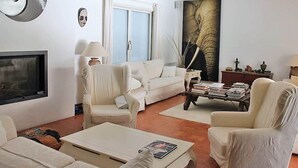 A living room with a sofa, armchairs, a coffee table, a TV, and a large elephant painting on the wall. - Luxury villa with heated jacuzzi and garden (Le Muy)