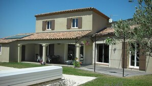 Une maison à deux étages dotée d’un patio, d’un espace salon extérieur couvert et d’une antenne parabolique.