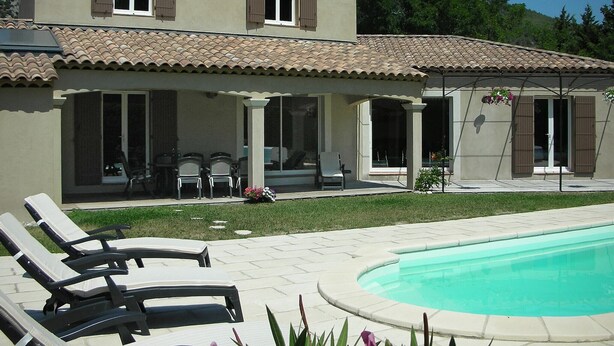 Une maison à deux étages dotée d’une piscine, d’un espace extérieur aménagé pour se détendre et d’un patio couvert.