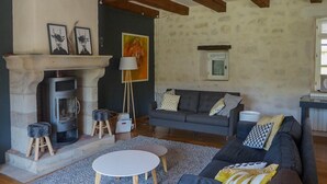 Una sala de estar acogedora con chimenea, un conjunto de sofás, una mesita redonda y una pared de piedra.